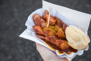 Frau  isst Currywurst unterwegs draußen am Wochenmarkt Imbiss