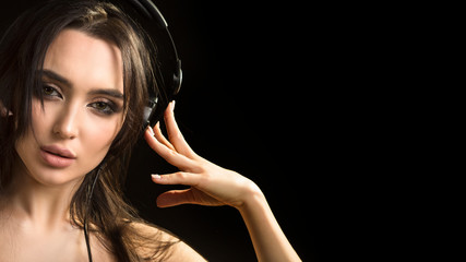 Fototapeta premium close up portrait of a woman, who listening to the music in headphones on dark background