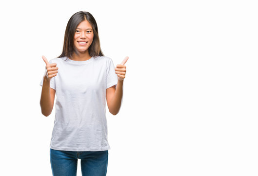 Young asian woman over isolated background success sign doing positive gesture with hand, thumbs up smiling and happy. Looking at the camera with cheerful expression, winner gesture.