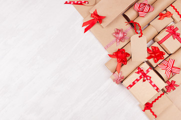 Fototapeta premium Gifts background for design advertising - set of craft paper presents with red bows, blank label on white wood board, top view, copy space.