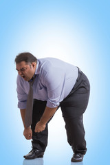 Obese man in formal clothes bending forward in pain