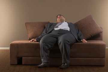 Obese businessman in formal clothes sleeping on sofa at home