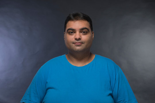 Portrait of smiling fat man against a black background