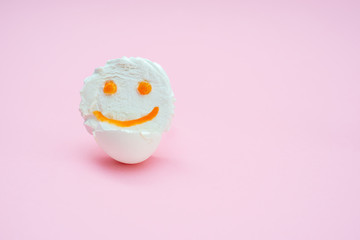 smile marshmallow in an egg shell on a pink background.