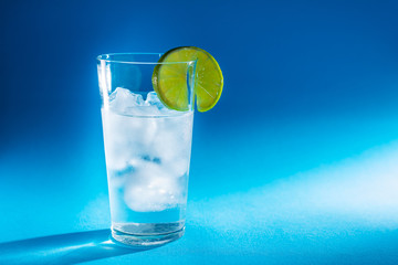 pure water in a glass of real ice and a slice of fresh lime in the rays of light