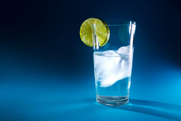 pure water in a glass of real ice and a slice of fresh lime in the rays of light
