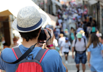 young boy with a straw hat photographs tourists