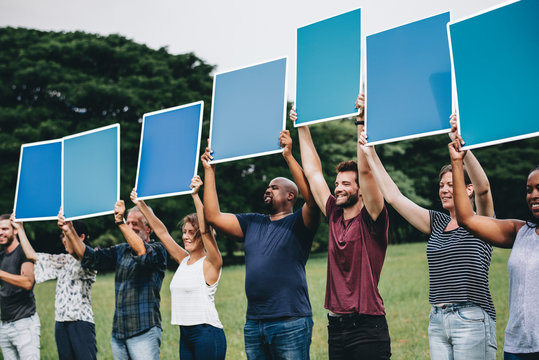 Diverse people holding blue squared boards in the park