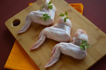 Fresh chicken wings for frying on wooden background.