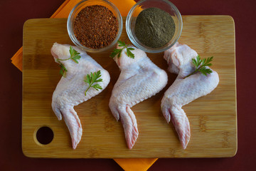 Fresh chicken wings for frying on wooden background.
