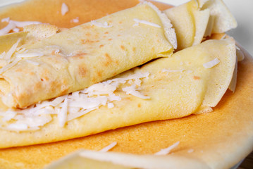 Pancakes rolled up in a tube with grated cheese are sprinkled