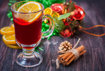 Hot wine (mulled wine) with spices on wooden background.