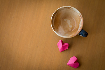 Valentines day concept, red paper hearts and a cup of coffee on a wooden desk background