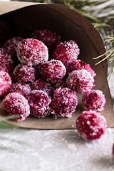 Candied cranberries in a crafting bag on the background of fir cones