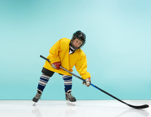 Obraz premium A hockey player in uniform with equipment over a blue studio background. The athlete, child, sport, action concept