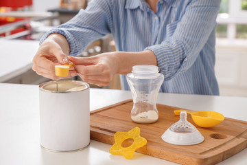 Woman preparing baby formula at table