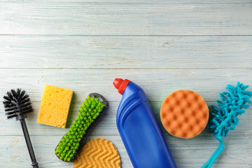 Flat lay composition with cleaning supplies on wooden background