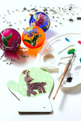 Girl draws deer paints on wooden mitten. Christmas gift.