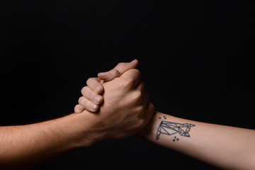 Man and woman holding hands on dark background