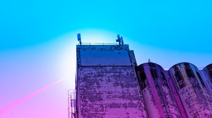 Old weathered building silo of a former paint store with well-worn colors and a red rope