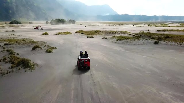 4K Tracking by drone on driving experience to Mt.Bromo, Pasuruan, East Java, Indonesia. Adventure driving Off-road Jeep 4WD into Beautiful active Volcano with smoke Mount Bromo.