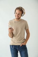 Handsome man listening to music on light background