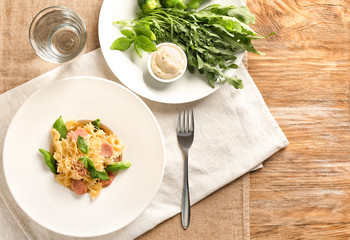 Plate with delicious macaroni and cut sausage on table