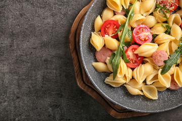 Pan with delicious macaroni, sausages and vegetables on table