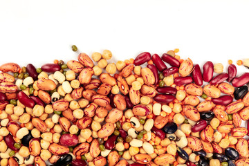 A photo of a mix of various types of legumes, shot from the top on a white background with a place for text. Different beans, lentils, chickpeas, soybeans. An abstract pulses texture with copy space