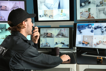 Security guard monitoring modern CCTV cameras in surveillance room
