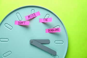 Paper sheets with text DON'T MISS THE DEADLINE on clock