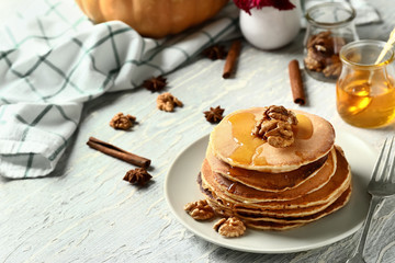 Stack of hot tasty pumpkin pancakes with honey and walnuts on plate