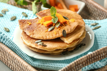 Hot tasty pancakes with pumpkin on wicker tray