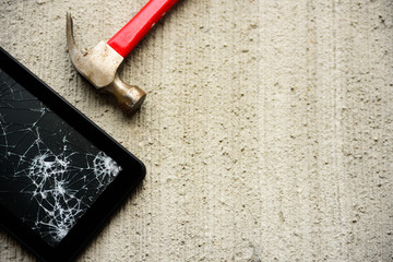 Broken tablet with hammer near it