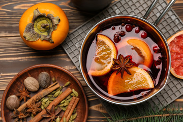 Pot of tasty mulled wine and ingredients on wooden background