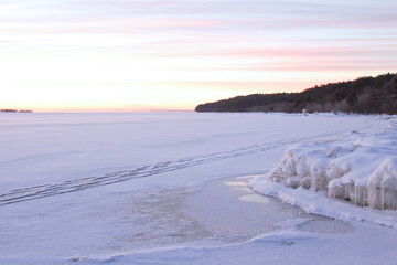 Idyllic northern snowscape with beautiful winter sunrise. Onega lake, Karelia, Russia