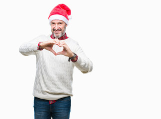 Fototapeta premium Middle age hoary senior man wearing christmas hat over isolated background smiling in love showing heart symbol and shape with hands. Romantic concept.