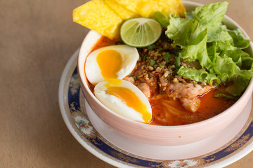 A noodle with spicy soup. Spicy lemongrass flavored flat noodles with pork and boiled egg