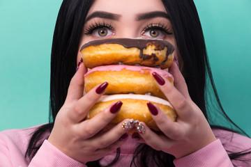 a portrait of a plus-size model covered her face with donuts and a picture on an azure background peering out at the viewer