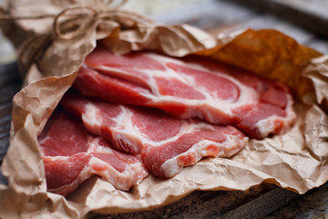 Fresh red chop meat on cooking paper. Dark red raw sliced meat on wooden table.