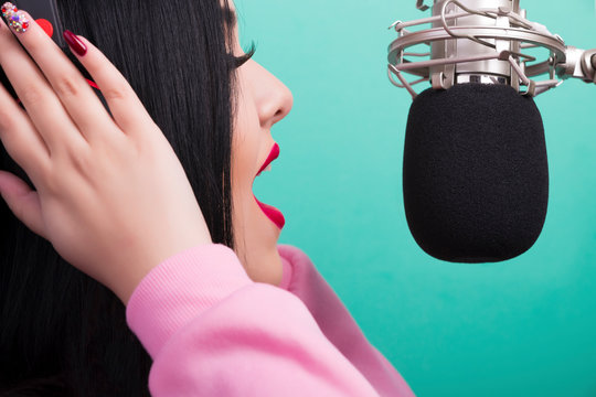 Closeup Portrait Of A Singing Girl With Red Lips And Studio Microphone On Azure Background