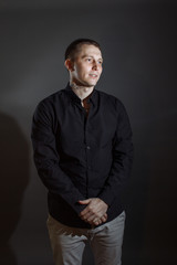 Portrait of determined goodlooking man wearing black shirt, black background.