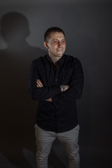 Portrait of determined goodlooking man wearing black shirt, black background.