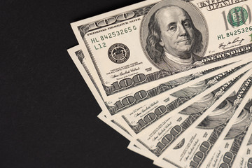 Fan of hundred dollar bills on the black surface on the right