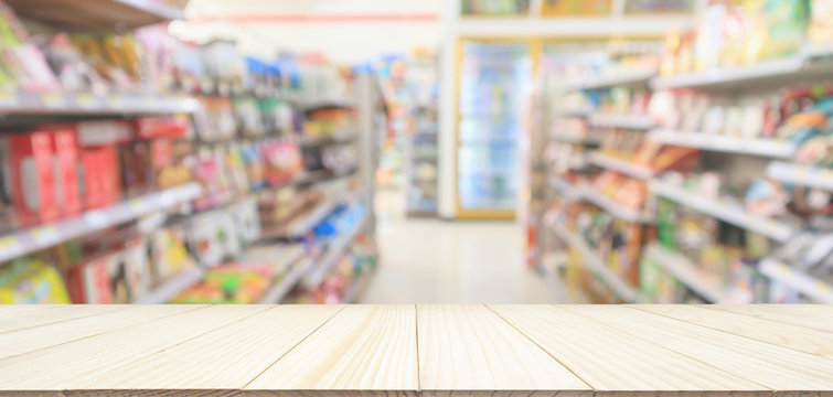 Wood table top with Supermarket convenience store aisle shelves interior blur for background