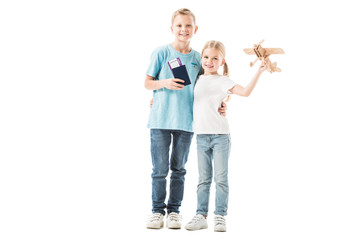 Obraz premium Sister and brother standing with passport and plane model isolated on white
