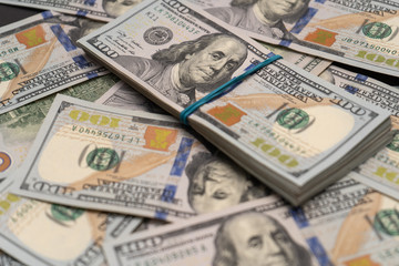 Fototapeta na wymiar Close-up. Pack of hundred dollar bills on the background of scattered bills