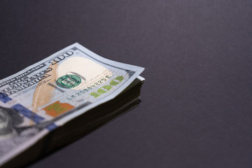 Pack of hunred dollar bills on black background