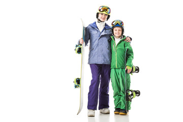 young mom and preteen son in ski suits with snowboards hugging isolated on white