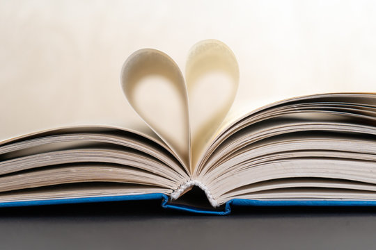 Close-up of an open book with heart shaped pages on white background